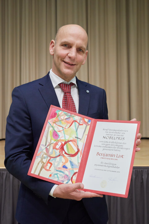 manbet手机版本杰明·李斯特展示他的诺贝尔奖证书。