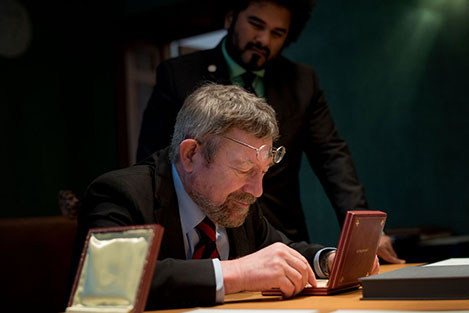 manbet手机版2016年12月12日，J. Michael Kosterlitz在访问诺贝尔基金会期间仔细查看了他的诺贝尔奖章。